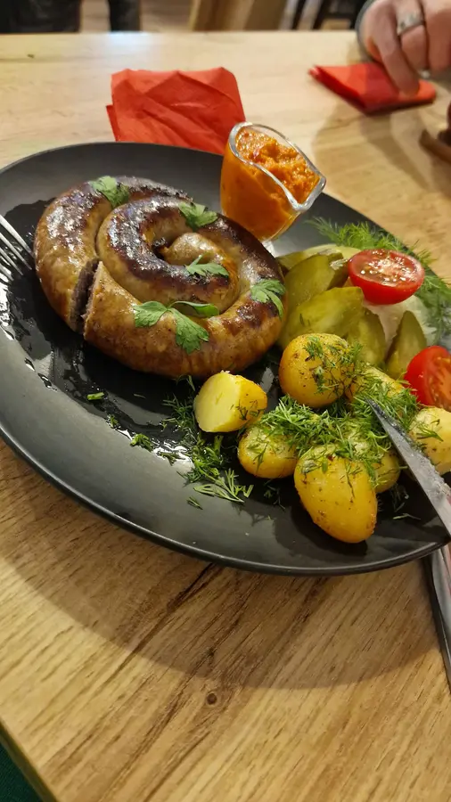 Gebratene Bauernwurst als Schnecke mit Kartoffeln, Dill, Gurken und Tomaten