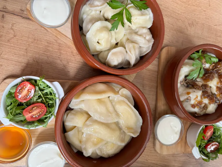 Wareniki und Pelmeni in Tontöpfen mit Sauerrahm, Salat und Honig